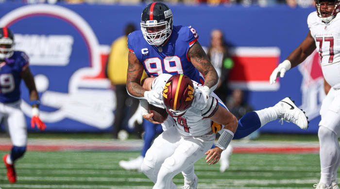 Giants defensive end Leonard Williams (99) sacks Commanders quarterback Sam Howell (14) during a game.